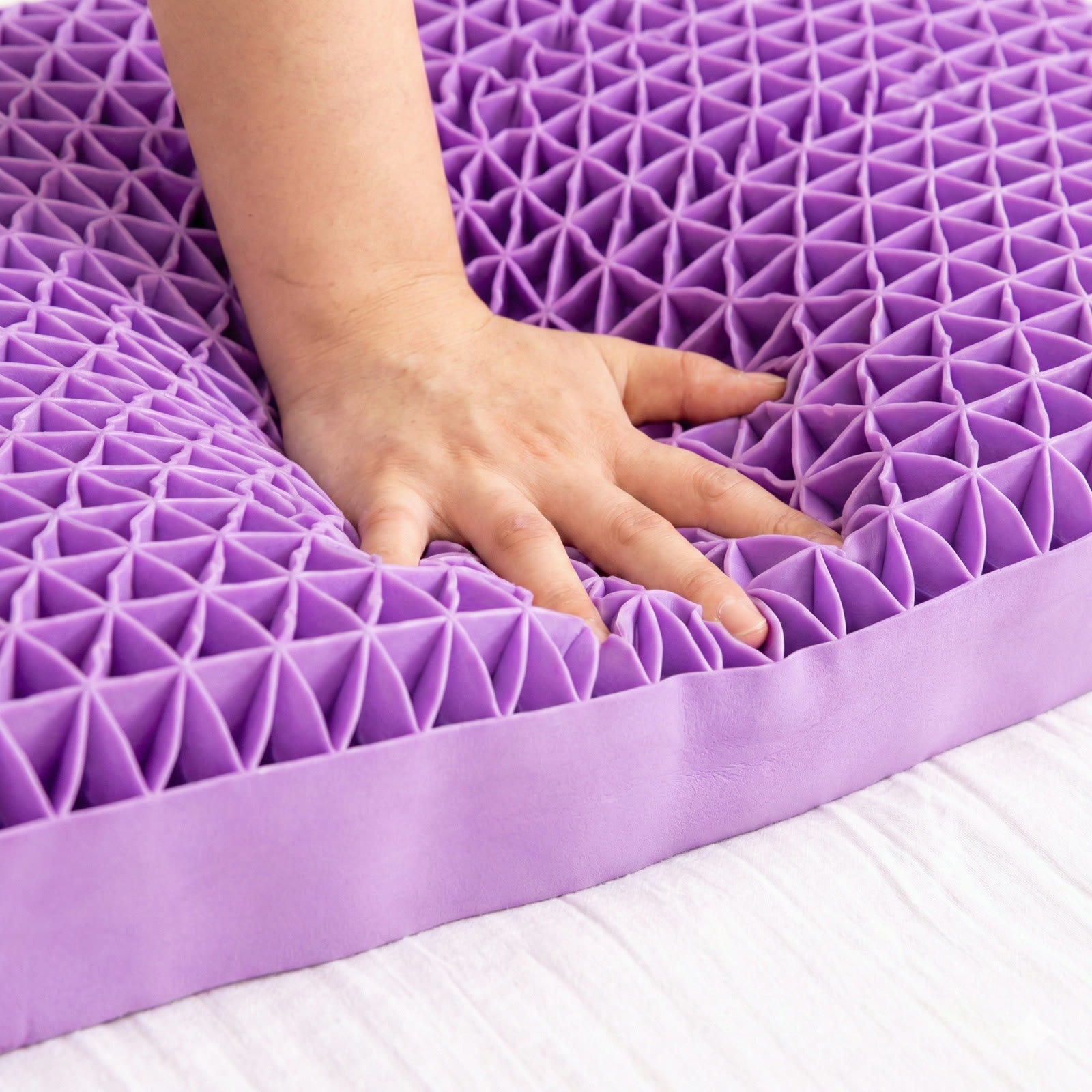 Une main presse la surface alvéolaire de l'oreiller DOZIA Sleep : les cellules se compriment localement sous les doigts